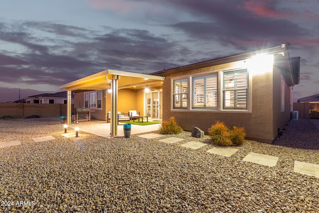 back house at dusk with cooling unit and a patio area