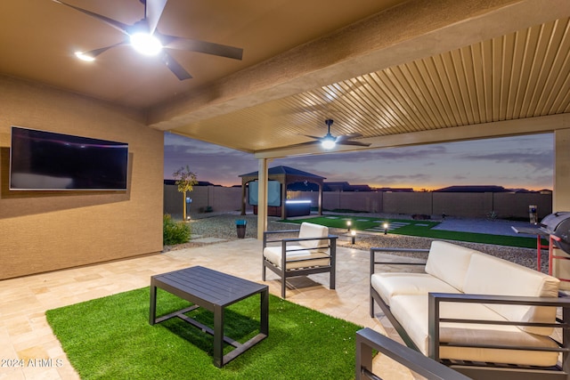 patio terrace at dusk with ceiling fan and an outdoor living space