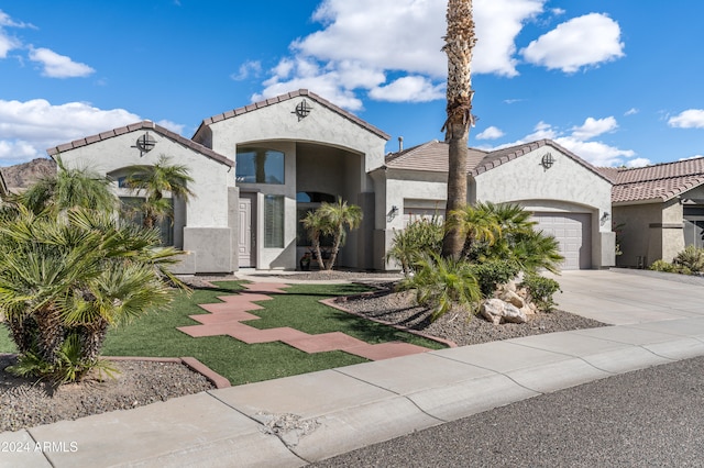 mediterranean / spanish-style home with a garage and a front lawn