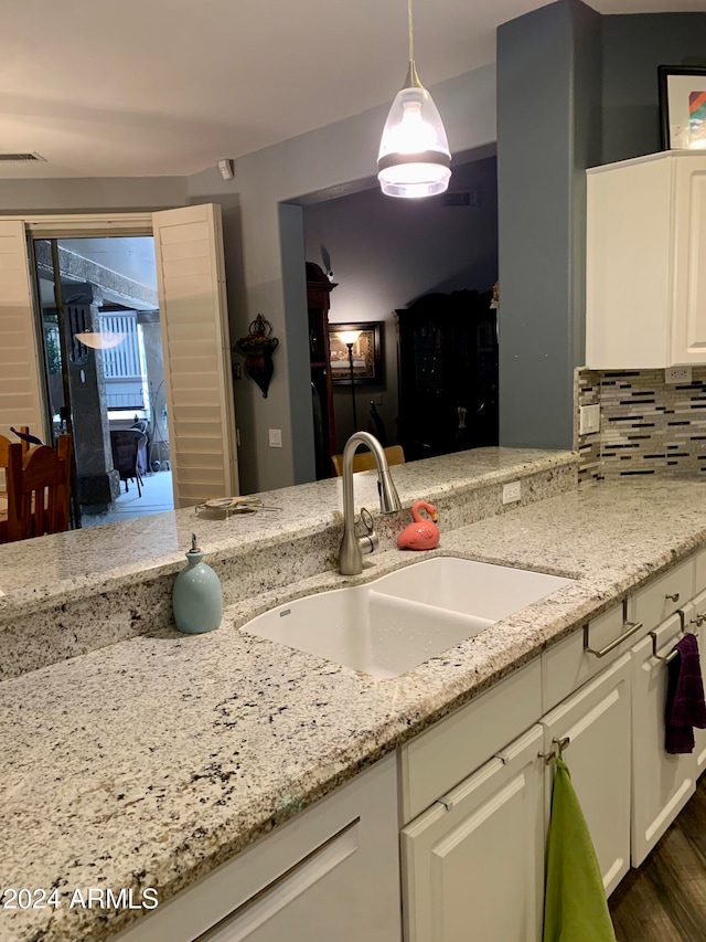 kitchen with light stone countertops, dark hardwood / wood-style flooring, tasteful backsplash, sink, and hanging light fixtures