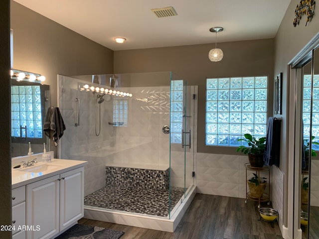 bathroom with hardwood / wood-style floors, vanity, and an enclosed shower