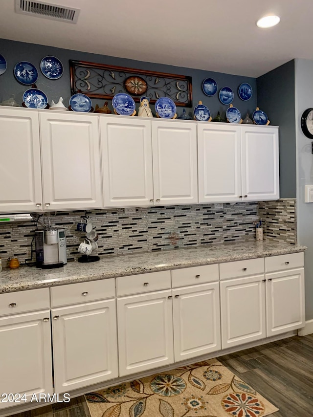 kitchen with dark hardwood / wood-style flooring, white cabinetry, and backsplash