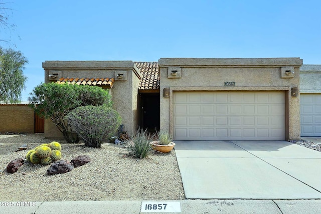 view of front facade featuring stucco siding, a garage, concrete driveway, and a tile roof