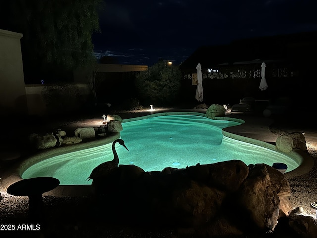 pool at night featuring a fenced in pool