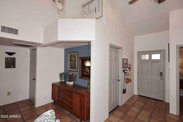 foyer with tile patterned flooring, a ceiling fan, visible vents, and high vaulted ceiling