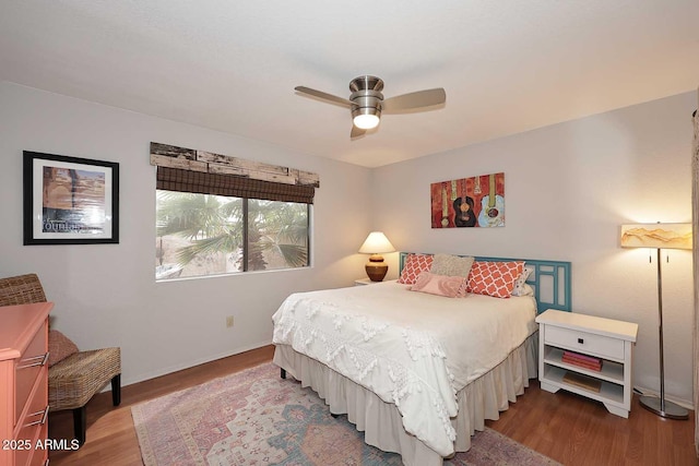 bedroom with a ceiling fan, wood finished floors, and baseboards