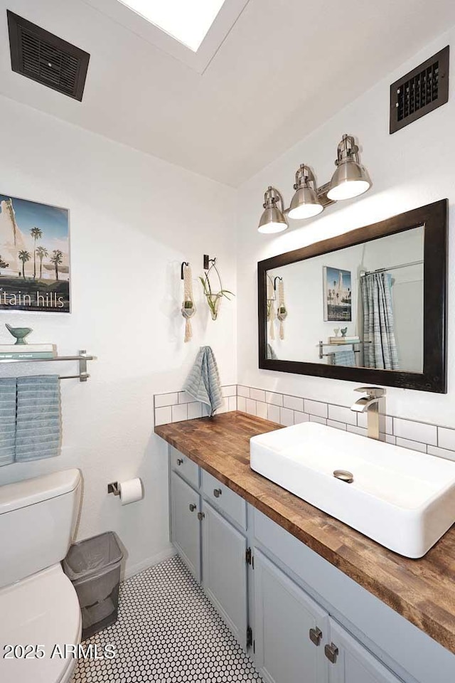 bathroom with visible vents, tasteful backsplash, toilet, and vanity