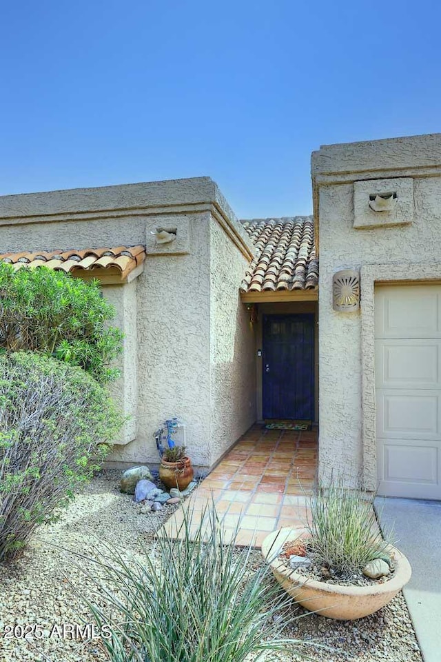 entrance to property featuring a tile roof and stucco siding