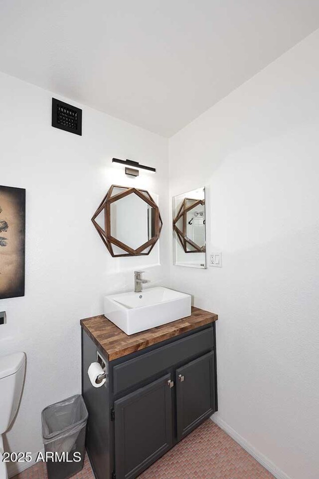 bathroom with toilet, vanity, and baseboards