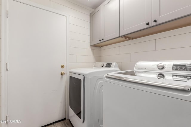 laundry area featuring cabinets, independent washer and dryer, and hardwood / wood-style floors