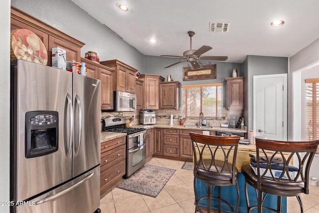 20769 N 106th Ln, Peoria, AZ 85382 - kitchen featuring stainless steel appliances, tasteful backsplash, a ceiling fan, light tile patterned floors, and light stone countertops