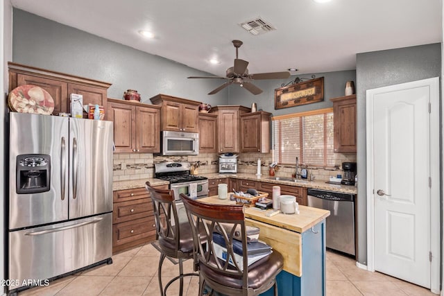20769 N 106th Ln, Peoria, AZ 85382 - kitchen with appliances with stainless steel finishes, decorative backsplash, light tile patterned floors, a ceiling fan, and brown cabinetry