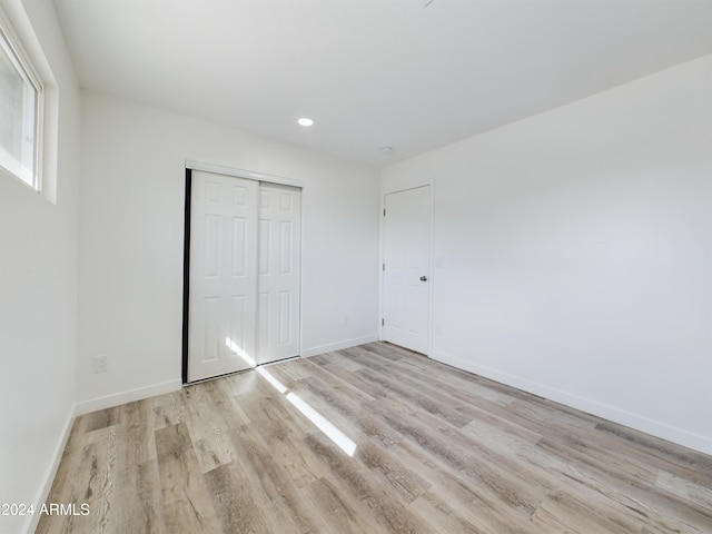 unfurnished bedroom with a closet and light wood-type flooring