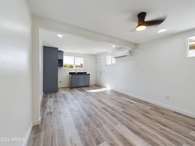 unfurnished living room featuring a wall mounted air conditioner, light hardwood / wood-style flooring, and ceiling fan