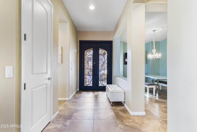 tiled entryway with french doors and a notable chandelier