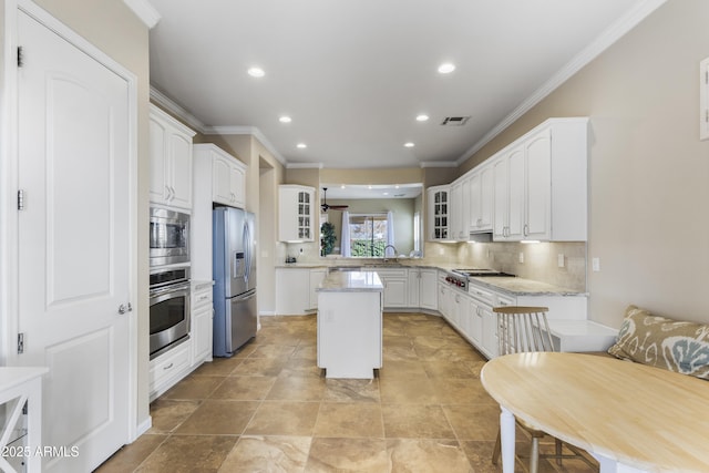 kitchen featuring white cabinetry, stainless steel appliances, a center island, and light stone counters