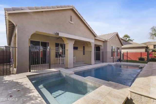 rear view of house featuring a swimming pool with hot tub, a patio, and ceiling fan