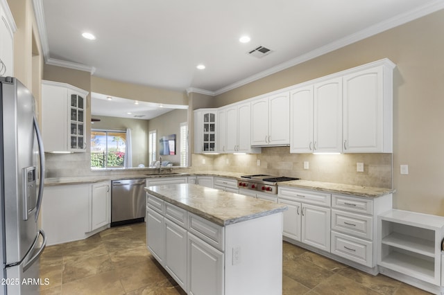 kitchen featuring appliances with stainless steel finishes, a center island, white cabinets, and backsplash