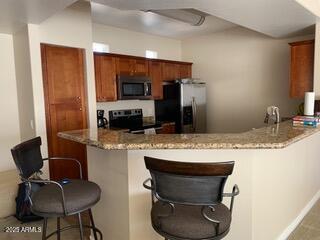 kitchen with light stone counters, stainless steel fridge with ice dispenser, a peninsula, and electric range oven