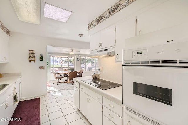 kitchen with oven, light tile patterned flooring, black electric cooktop, ceiling fan, and white cabinets