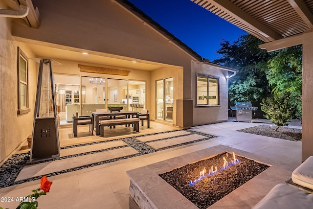 patio at night with an outdoor fire pit, a wall mounted air conditioner, and a grill