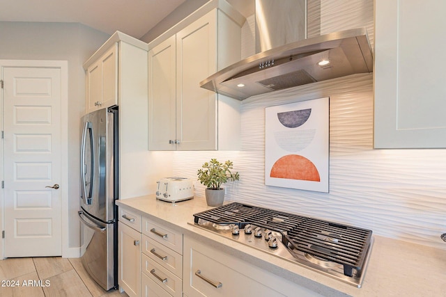 kitchen featuring white cabinets, appliances with stainless steel finishes, and wall chimney exhaust hood