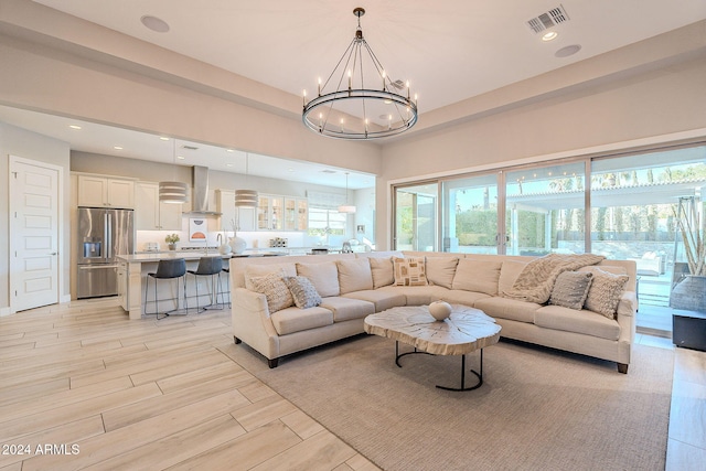 living room featuring light wood-type flooring, a chandelier, and sink