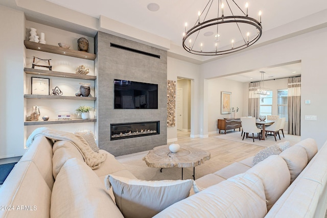 living room with a large fireplace, light hardwood / wood-style flooring, and a notable chandelier