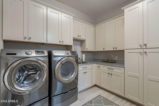 laundry area featuring separate washer and dryer, cabinets, and light wood-type flooring