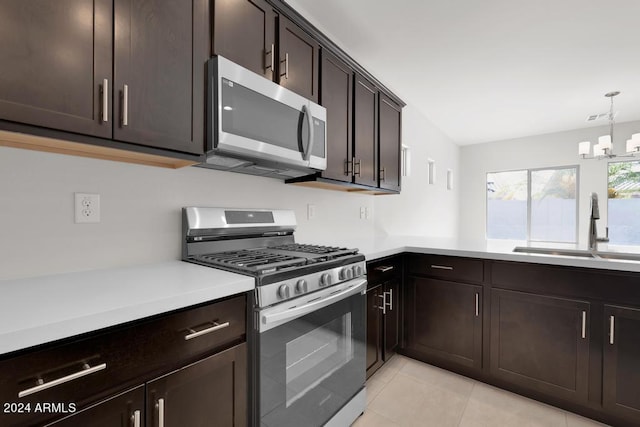 kitchen featuring stainless steel appliances, a sink, light tile patterned floors, a chandelier, and light countertops