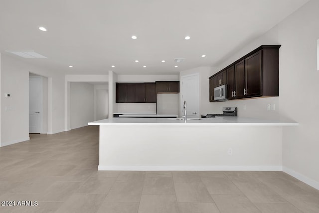 kitchen featuring appliances with stainless steel finishes, light countertops, dark brown cabinets, recessed lighting, and a peninsula