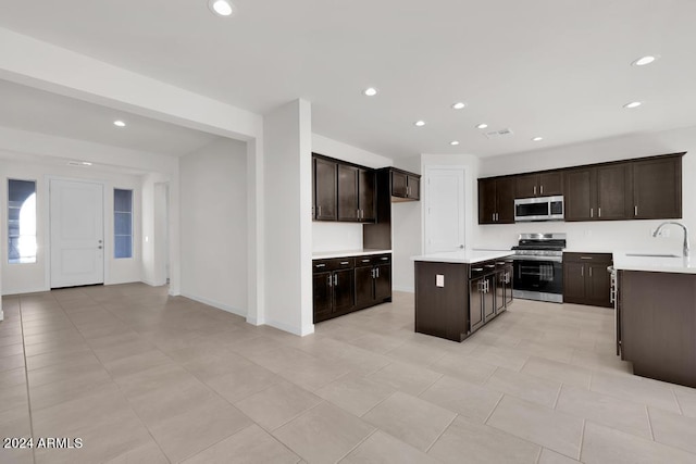 kitchen with stainless steel appliances, a sink, dark brown cabinets, light countertops, and recessed lighting
