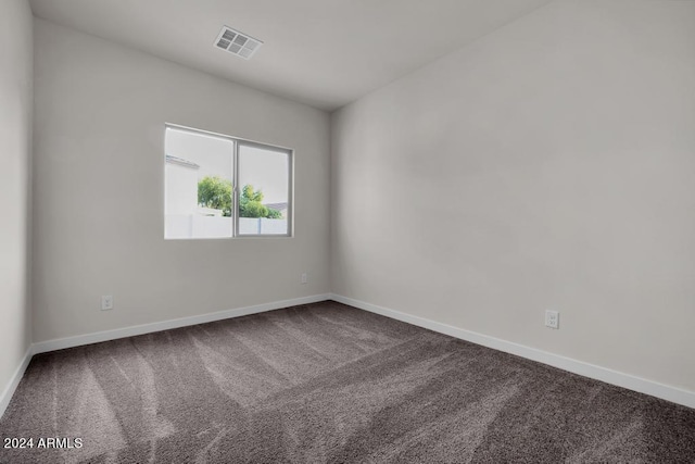 empty room featuring dark colored carpet and baseboards