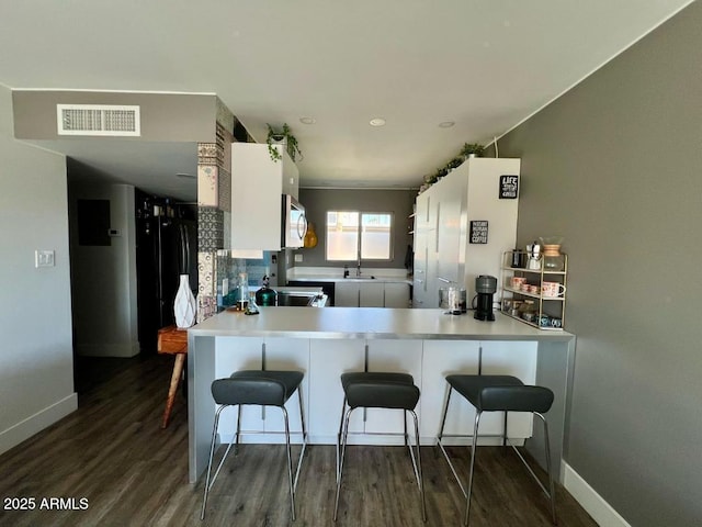 4610 N 68th St N Unit 476, Scottsdale, AZ 85251 - kitchen featuring dark wood finished floors, a kitchen bar, a peninsula, and stainless steel microwave