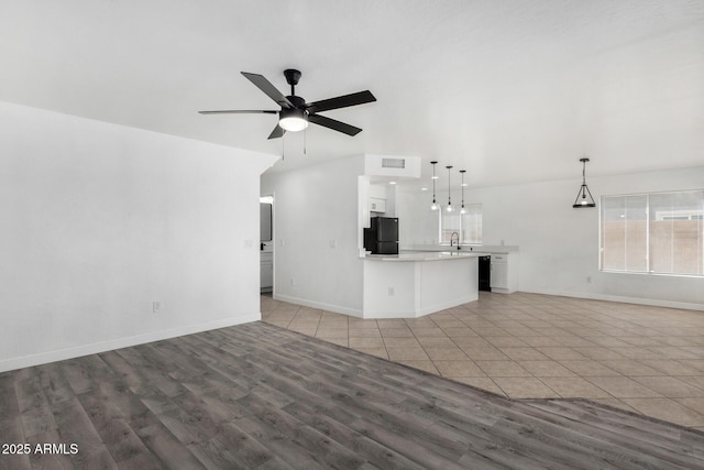 unfurnished living room with visible vents, light wood finished floors, baseboards, a ceiling fan, and a sink