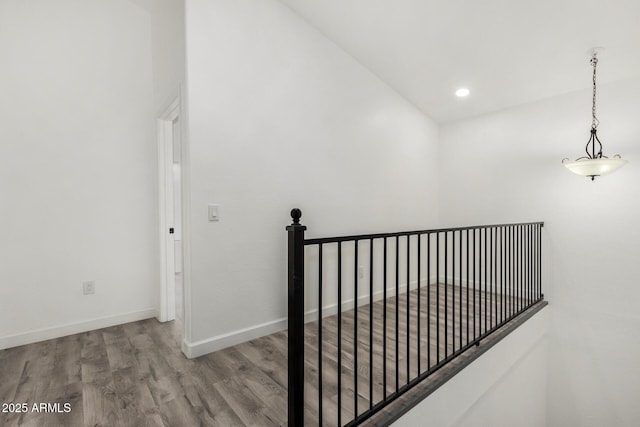 interior space featuring baseboards, an upstairs landing, wood finished floors, and recessed lighting
