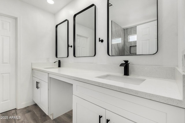 full bathroom with double vanity, a sink, walk in shower, and wood finished floors