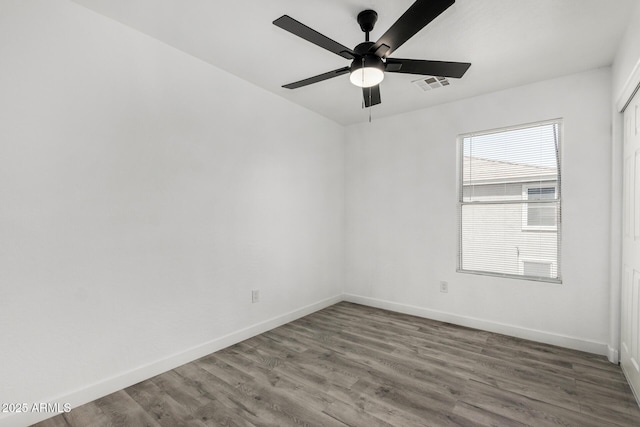 spare room featuring baseboards, visible vents, and wood finished floors