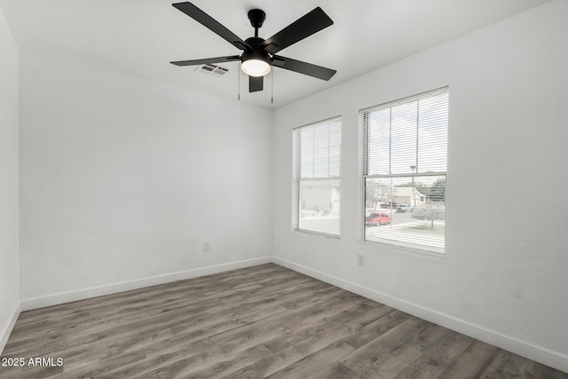 unfurnished room featuring baseboards, visible vents, ceiling fan, and wood finished floors
