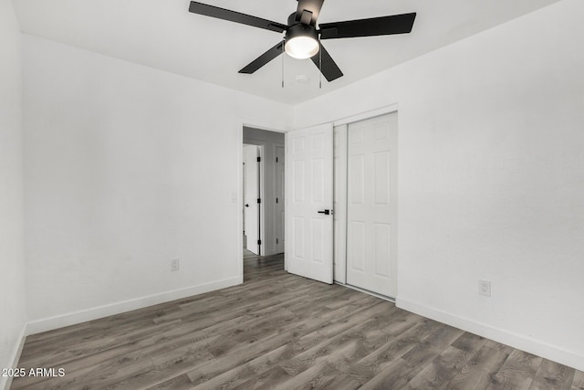 unfurnished bedroom with a closet, baseboards, ceiling fan, and wood finished floors