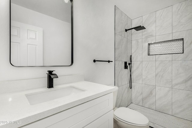 bathroom featuring toilet, tiled shower, and vanity