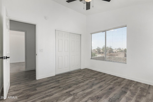 unfurnished bedroom with baseboards, a closet, ceiling fan, and dark wood-type flooring
