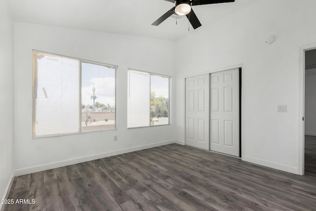 unfurnished bedroom with a closet, a ceiling fan, lofted ceiling, baseboards, and dark wood-style flooring
