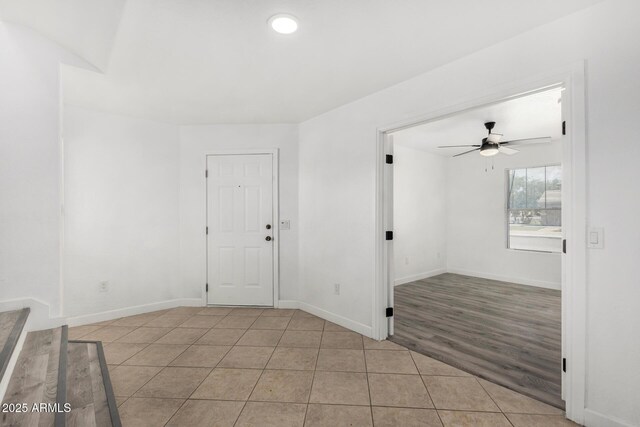 spare room featuring baseboards, ceiling fan, and light tile patterned floors