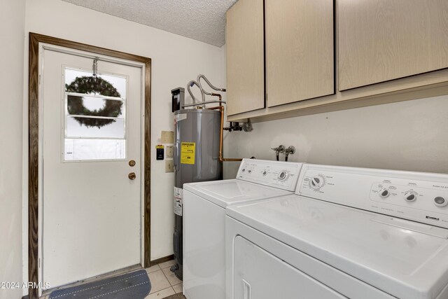 laundry area with washer and clothes dryer, cabinets, a textured ceiling, water heater, and light tile patterned flooring