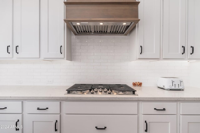 kitchen with stainless steel gas cooktop, white cabinets, and custom exhaust hood