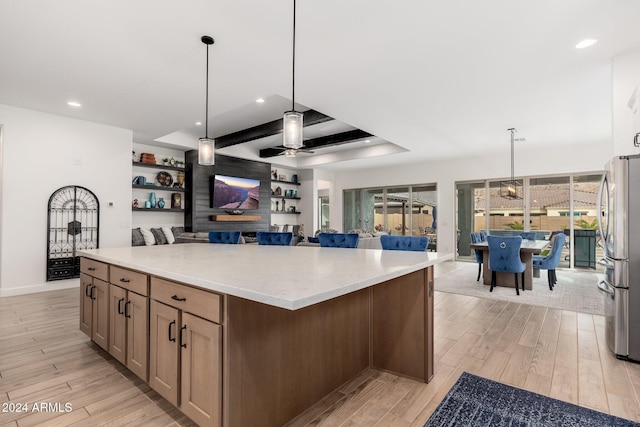 kitchen featuring pendant lighting, light hardwood / wood-style flooring, ceiling fan, a kitchen island, and stainless steel refrigerator