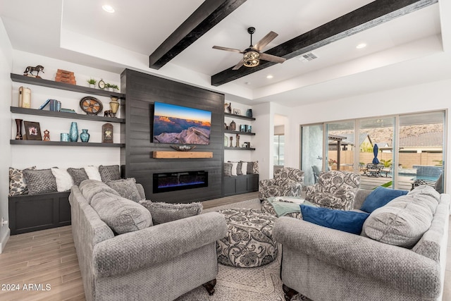 living room with beam ceiling, a fireplace, ceiling fan, and light hardwood / wood-style flooring