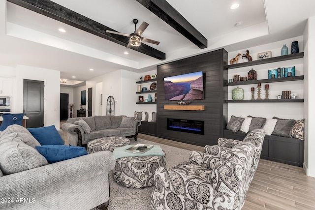 living room with a fireplace, light hardwood / wood-style floors, ceiling fan, and beamed ceiling