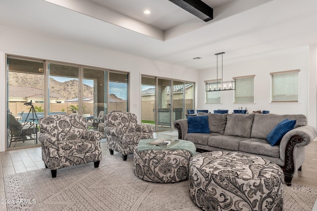 living room featuring beam ceiling, a mountain view, light hardwood / wood-style flooring, and a chandelier